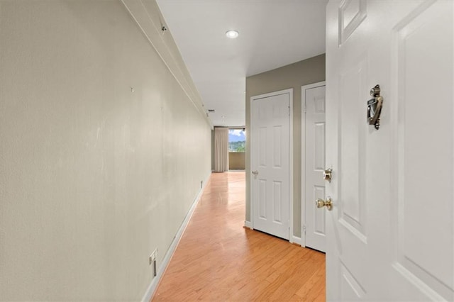 hallway featuring light wood-style flooring and baseboards