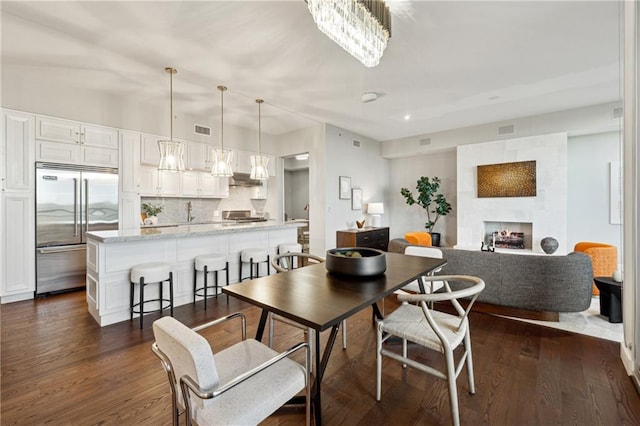 dining area with a chandelier, a fireplace, and dark wood-type flooring