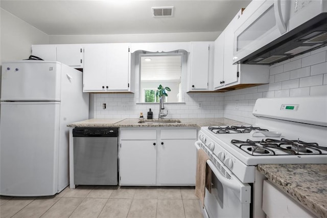 kitchen with white appliances, a sink, light tile patterned floors, white cabinetry, and decorative backsplash