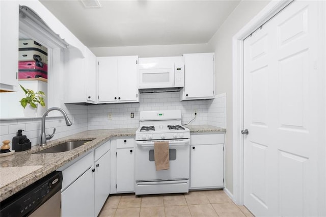kitchen featuring white appliances, a sink, white cabinets, and backsplash