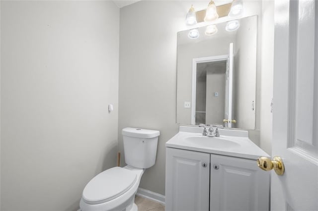 half bath with toilet, vanity, and tile patterned floors