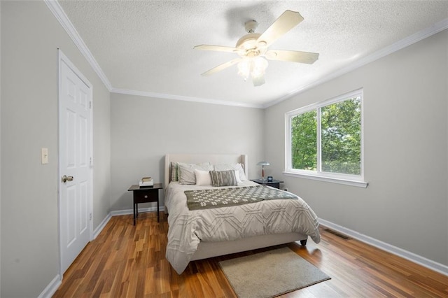 bedroom featuring wood finished floors, a textured ceiling, baseboards, a ceiling fan, and crown molding