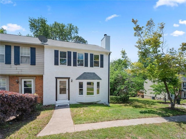 townhome / multi-family property featuring a chimney, brick siding, and a front lawn