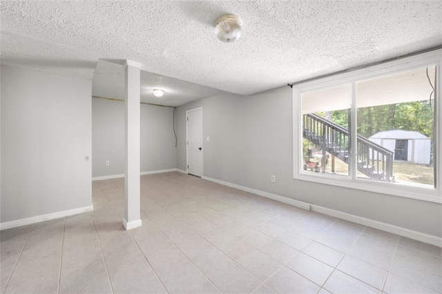 basement featuring a textured ceiling, light tile patterned floors, and baseboards