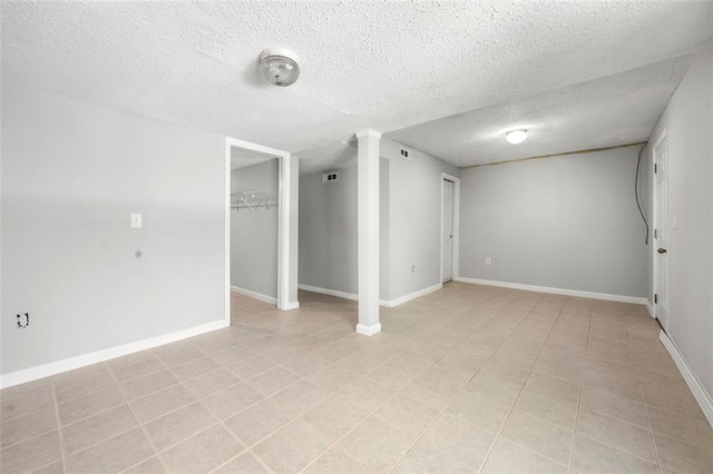empty room with a textured ceiling, baseboards, and light tile patterned floors