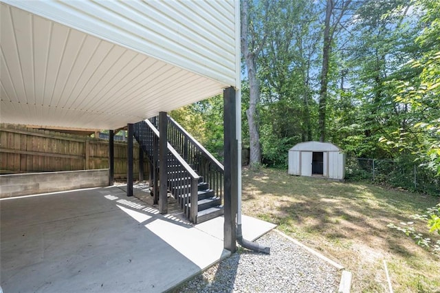 view of patio with stairway, a fenced backyard, a shed, and an outbuilding