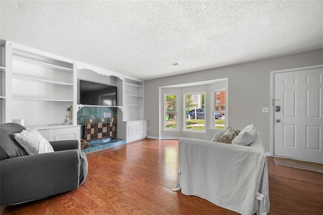 living room featuring a textured ceiling, wood finished floors, and built in shelves