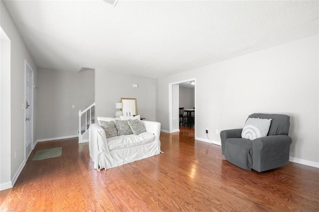living room with wood finished floors, stairs, and baseboards