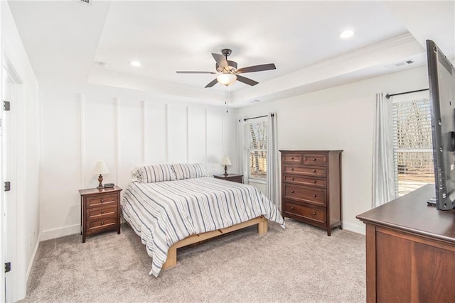 bedroom with light carpet, ceiling fan, and a tray ceiling