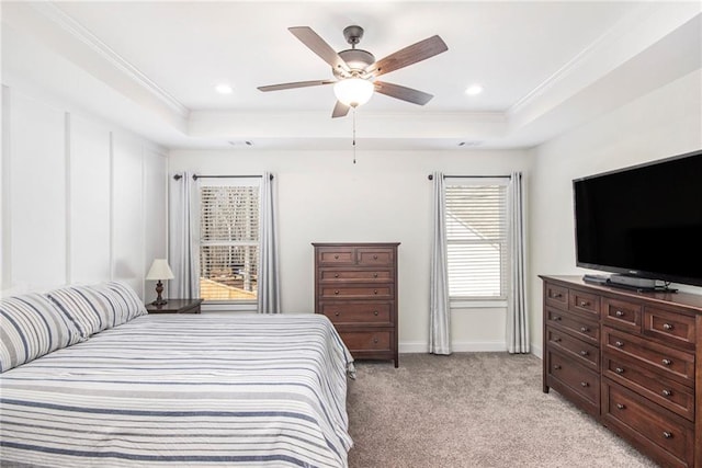 bedroom featuring light carpet, a tray ceiling, crown molding, and ceiling fan