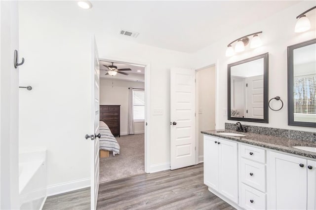 bathroom with hardwood / wood-style flooring, vanity, and a bath