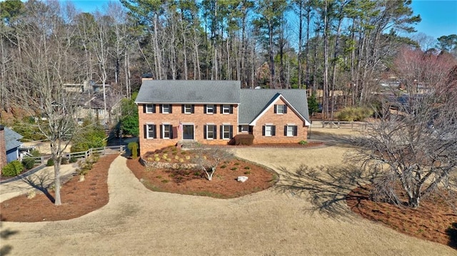 colonial house featuring dirt driveway and fence