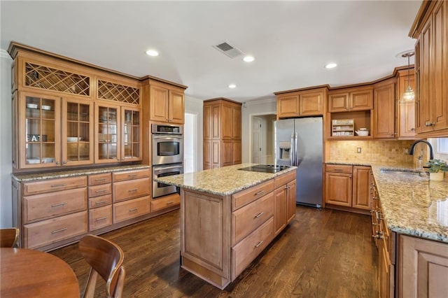 kitchen featuring light stone counters, a sink, visible vents, appliances with stainless steel finishes, and a center island