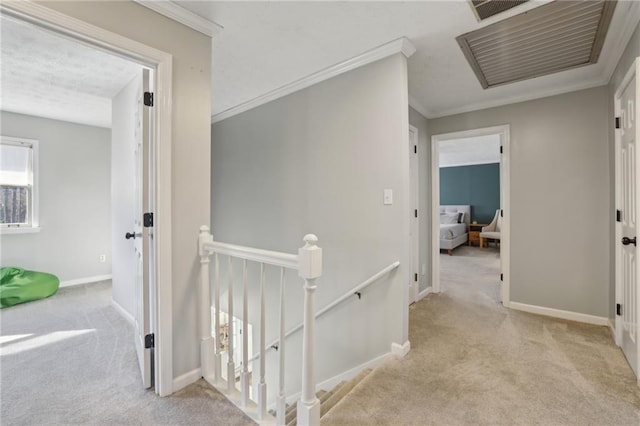 hall with carpet floors, baseboards, crown molding, and an upstairs landing