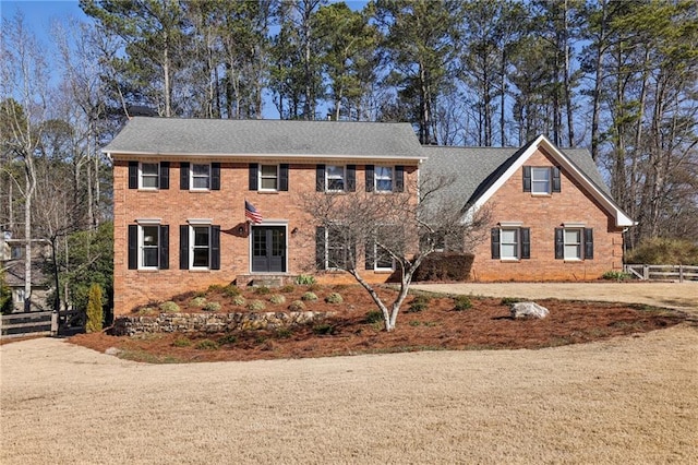 colonial-style house featuring brick siding and fence