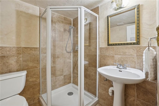 bathroom with a stall shower, tile walls, and toilet