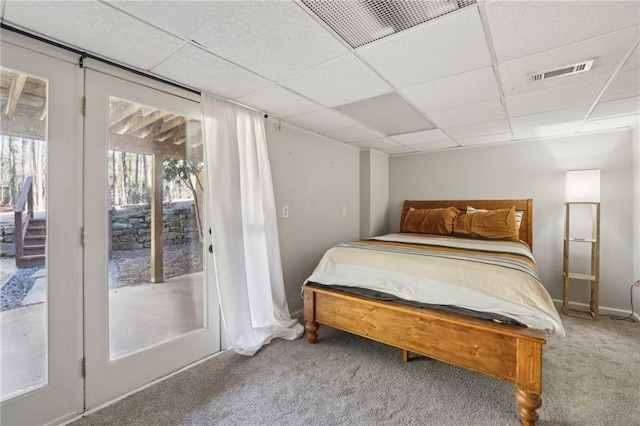 carpeted bedroom with a paneled ceiling, baseboards, and visible vents