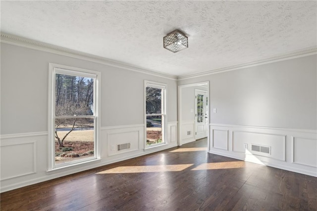 unfurnished room with visible vents, crown molding, a textured ceiling, and wood finished floors