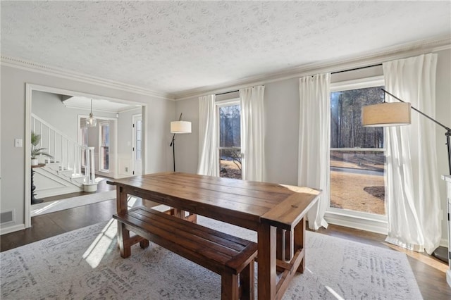 dining space with a textured ceiling, stairs, ornamental molding, and wood finished floors