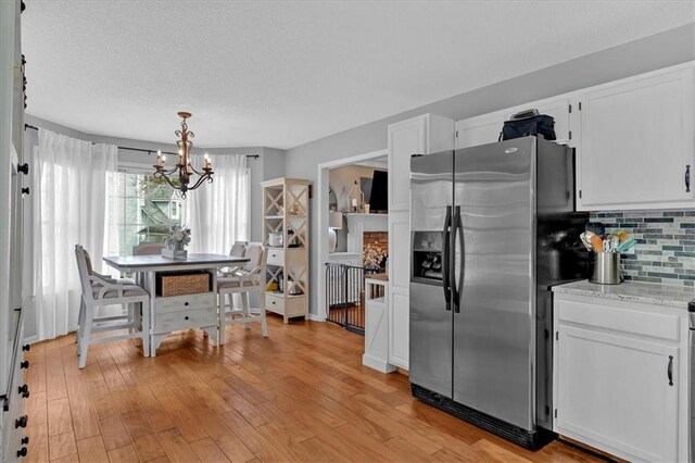 127 Hyde Way, Dallas, GA 30157 - kitchen with backsplash, stainless steel fridge, white cabinetry, and an inviting chandelier
