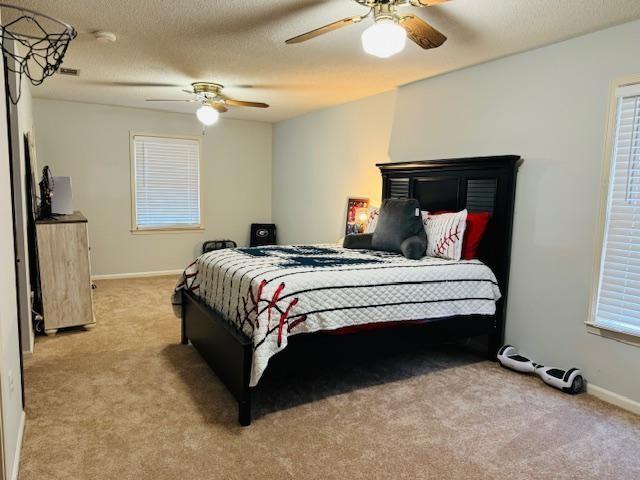 carpeted bedroom featuring ceiling fan and a textured ceiling