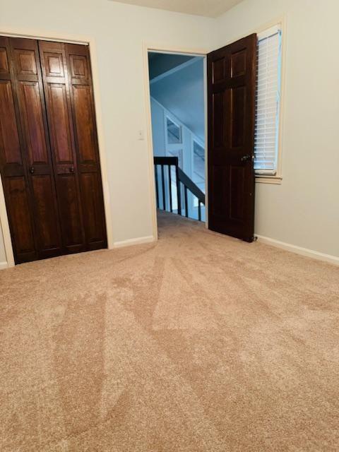 unfurnished bedroom featuring light carpet and a closet