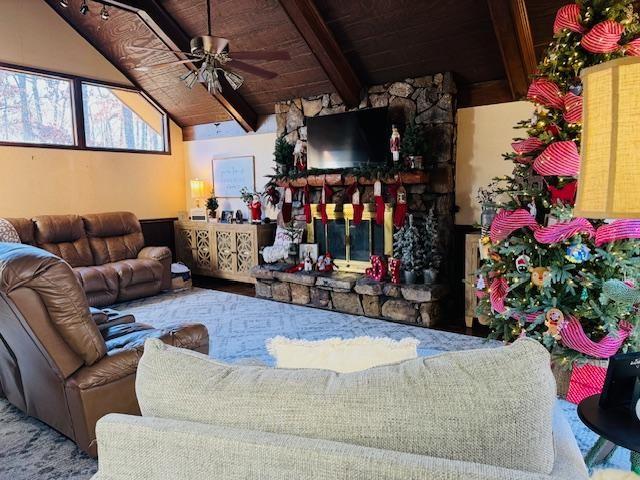 living room featuring ceiling fan, lofted ceiling with beams, and wooden ceiling