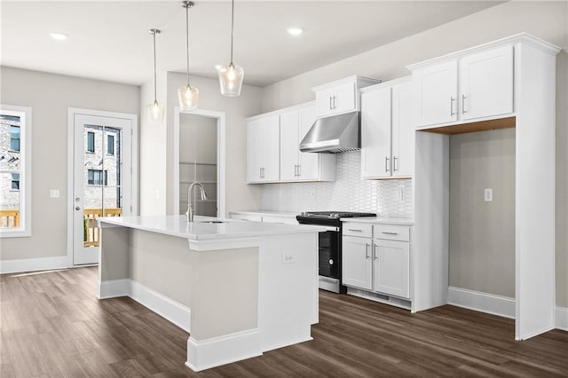 kitchen featuring stainless steel gas stove, an island with sink, hanging light fixtures, range hood, and white cabinetry