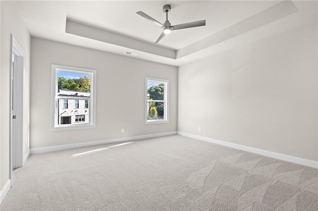 carpeted spare room featuring a tray ceiling and ceiling fan