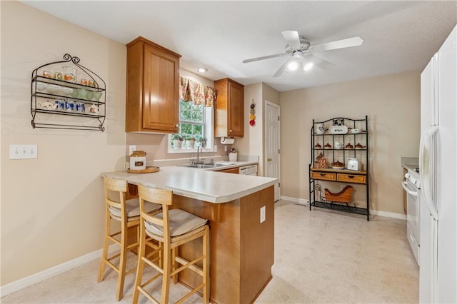 6960 Worley Rd, Cumming, GA 30028 - kitchen with a sink, brown cabinets, light countertops, a peninsula, and a ceiling fan