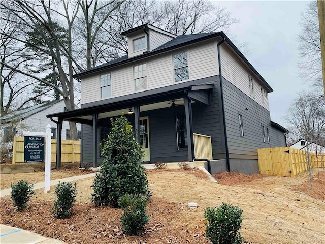 american foursquare style home with a ceiling fan, a porch, and fence