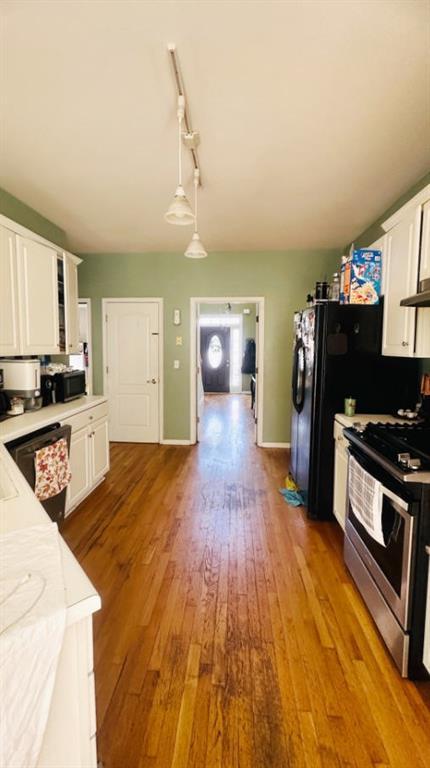 kitchen with wood finished floors, stainless steel range with gas cooktop, glass insert cabinets, and white cabinets