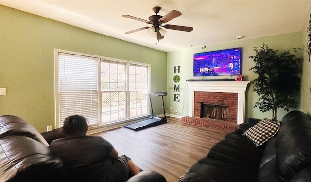 living area with a fireplace, a ceiling fan, and wood finished floors