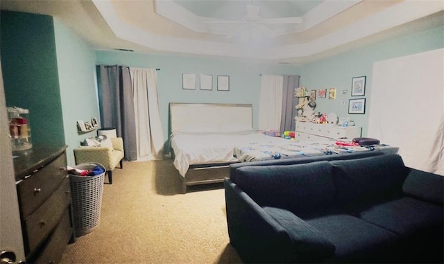 carpeted bedroom featuring a ceiling fan and a raised ceiling