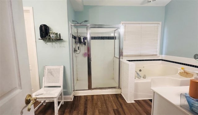 bathroom featuring a garden tub, a shower stall, and wood finished floors