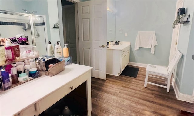 full bathroom with a stall shower, wood finished floors, vanity, and baseboards