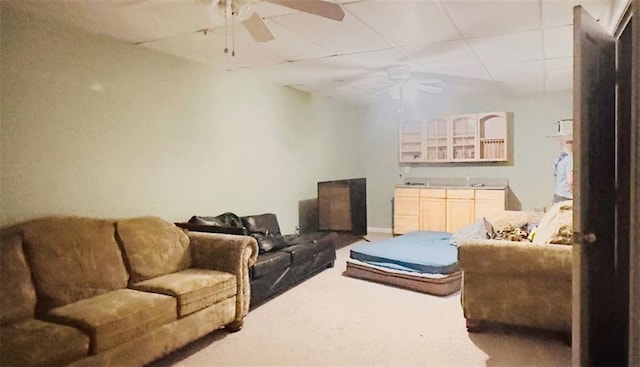 living area featuring ceiling fan, a drop ceiling, and carpet flooring