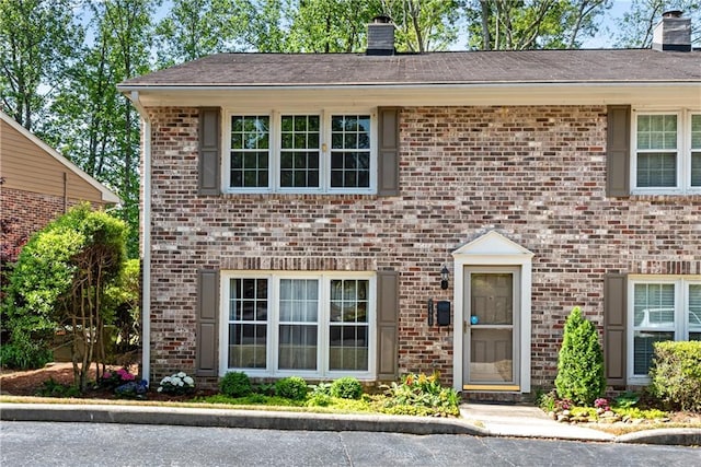 view of front of home featuring a chimney and brick siding