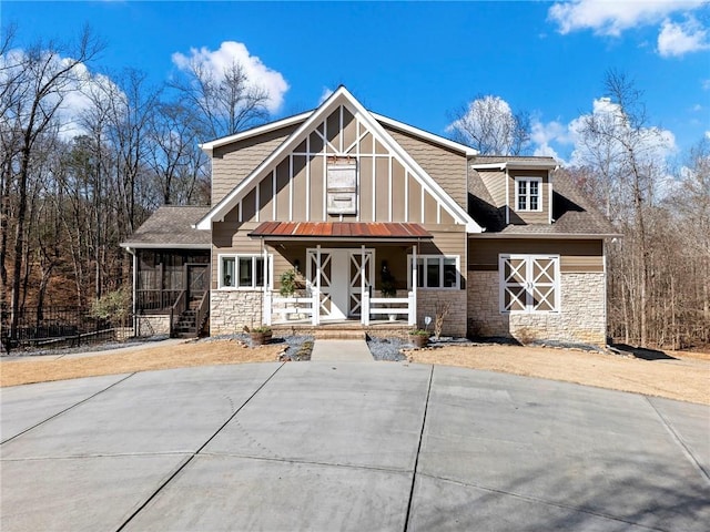 view of front of house with board and batten siding, stone siding, covered porch, and a shingled roof