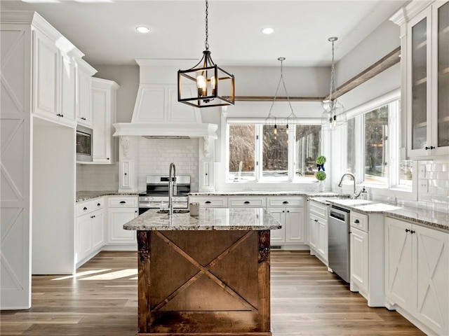 kitchen featuring decorative backsplash, appliances with stainless steel finishes, white cabinetry, a sink, and light wood-type flooring