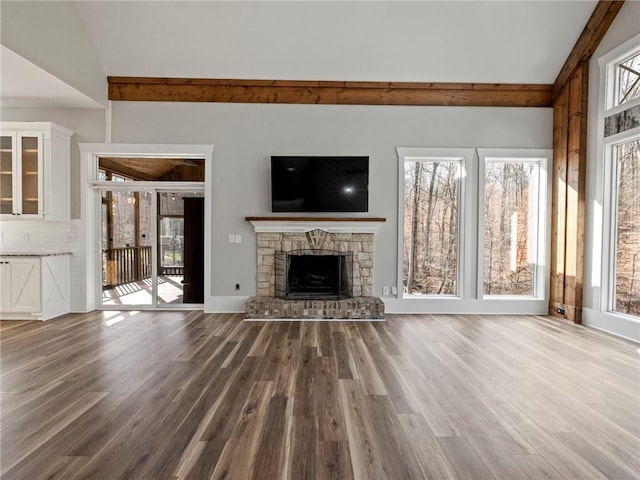 unfurnished living room with vaulted ceiling, a fireplace, and wood finished floors