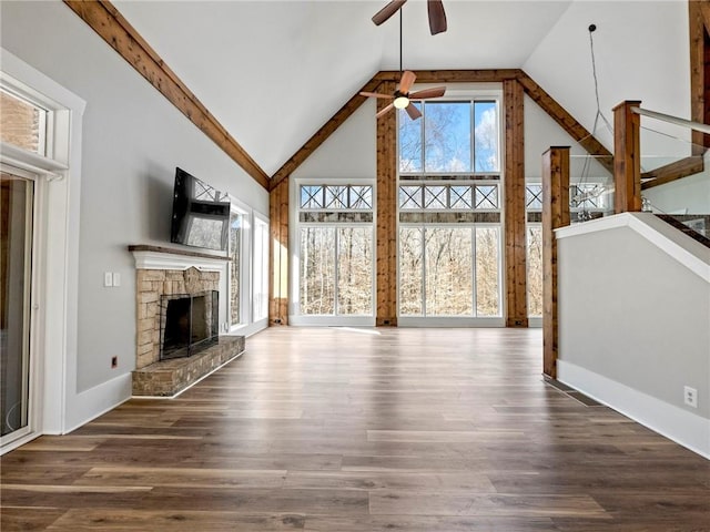 unfurnished living room with ceiling fan, high vaulted ceiling, a fireplace, wood finished floors, and baseboards