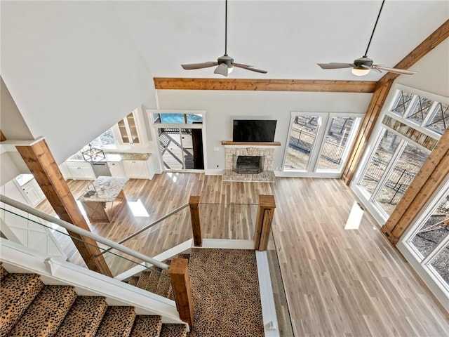 living area featuring high vaulted ceiling, a fireplace, plenty of natural light, and wood finished floors