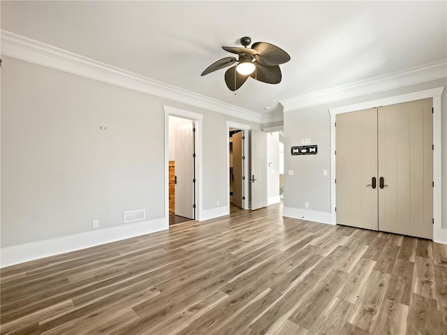 interior space with a closet, visible vents, crown molding, and wood finished floors