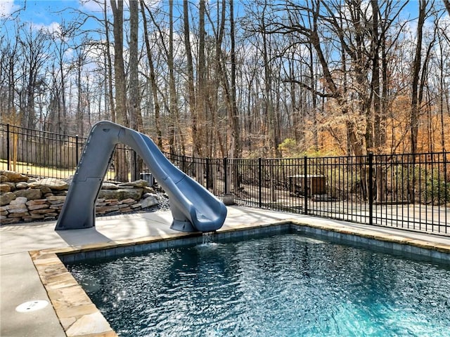 view of pool with a water slide and fence