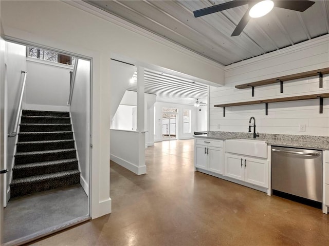 kitchen with a sink, concrete floors, open shelves, and stainless steel dishwasher