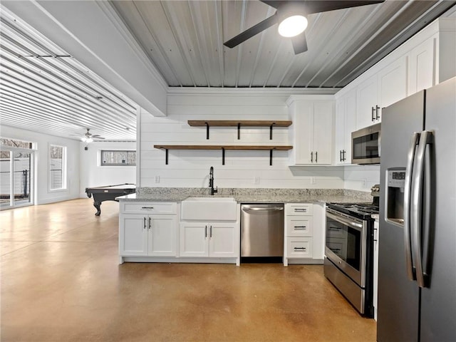 kitchen with stainless steel appliances, concrete flooring, a sink, and open shelves