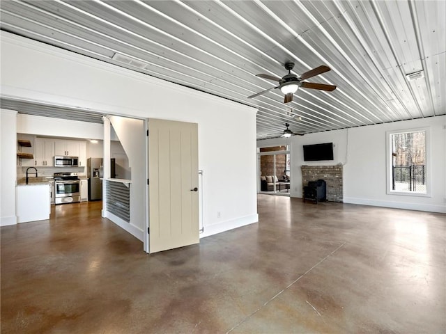 unfurnished living room featuring baseboards, a fireplace, a sink, and finished concrete floors