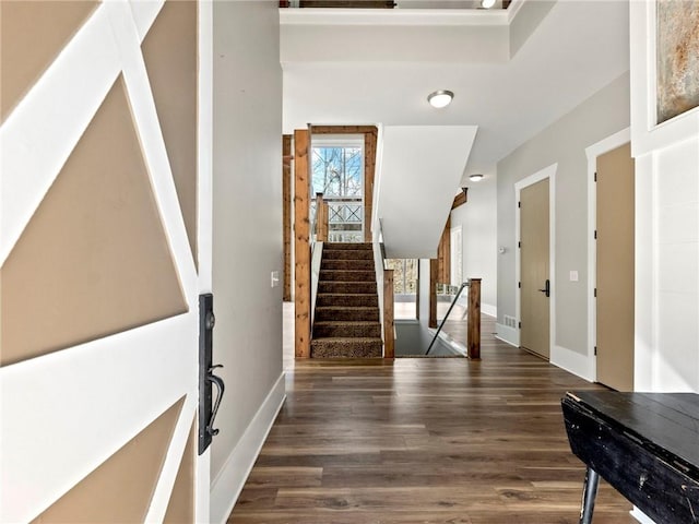 foyer featuring wood finished floors, a towering ceiling, and baseboards