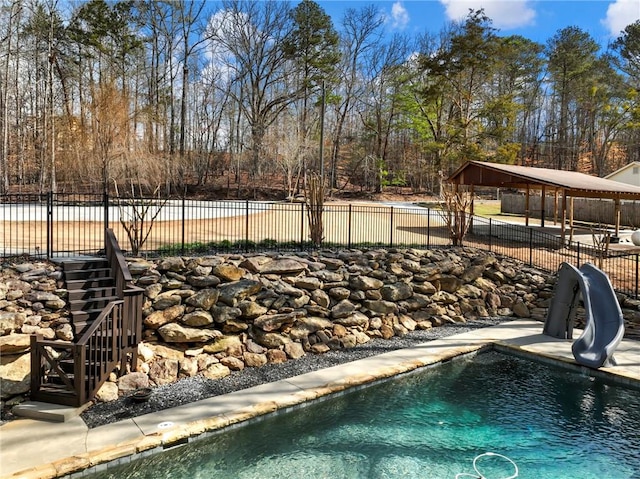 view of swimming pool with a fenced in pool, a water slide, fence, and stairway